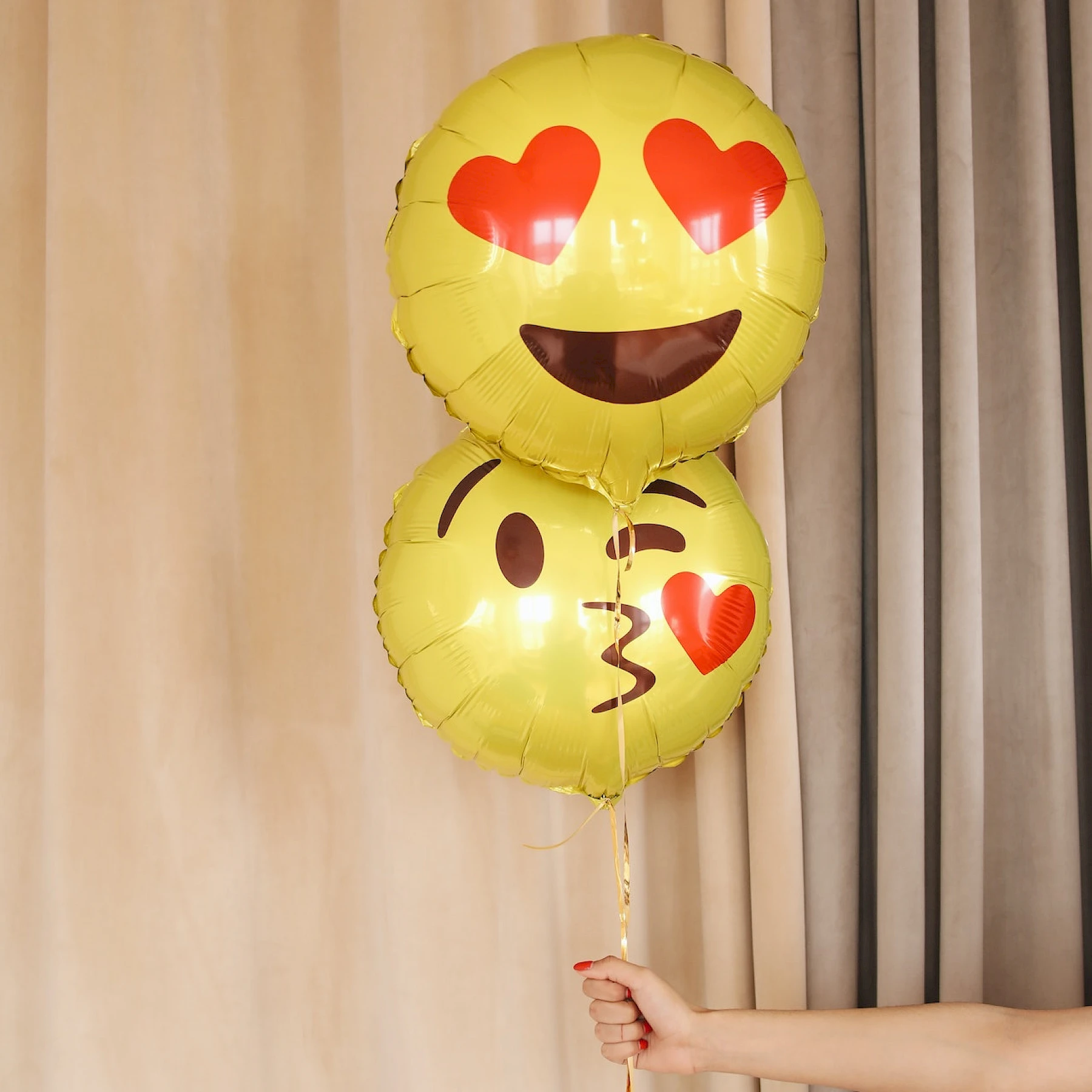 Kaksi emoji-ilmapalloa. Toinen emoji antaa suukon ja toisella on silmien tilalla sydämet.